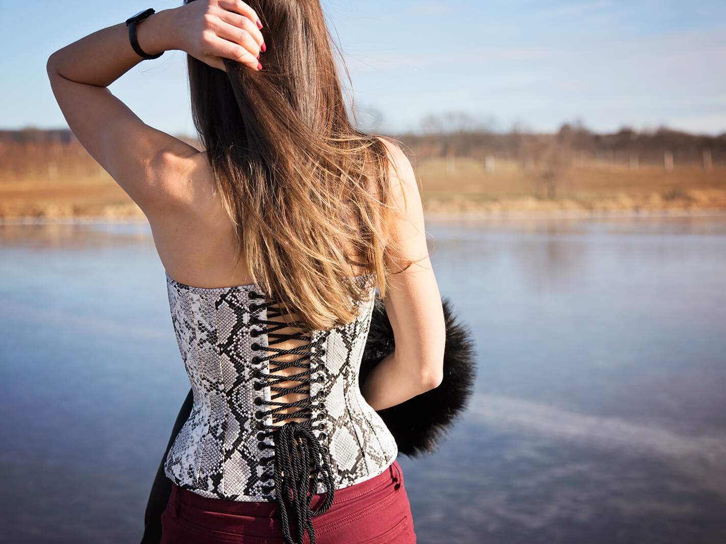 Woman in Corset and Red Pants Standing by Lake