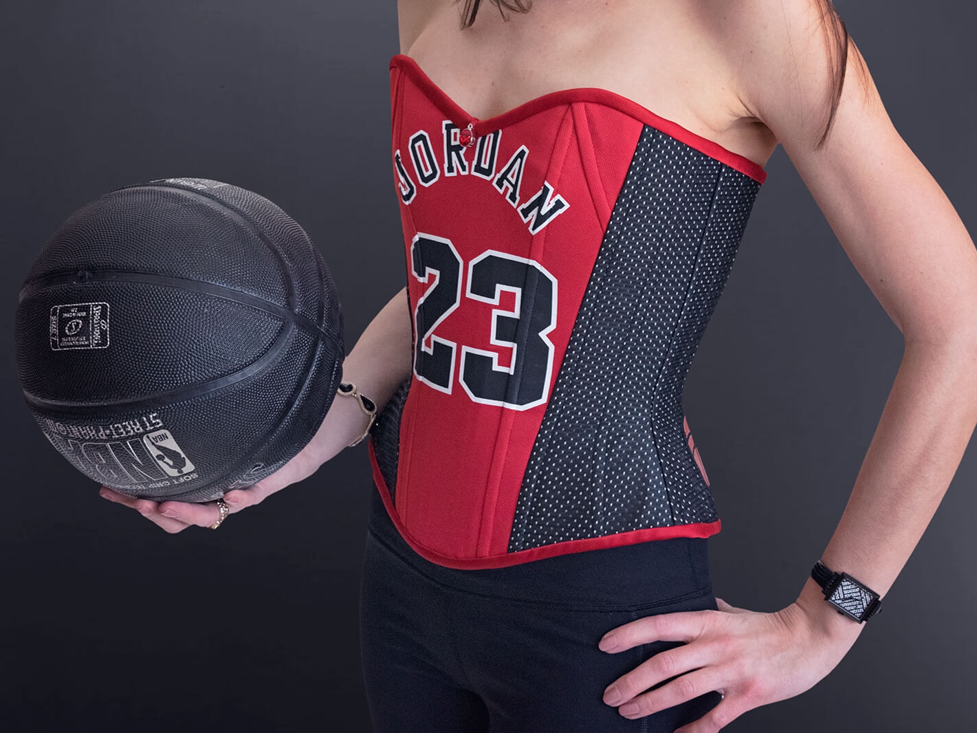 Stella holding basketball wearing her Chicago Bulls Michael Jordan Corset #23 on black background